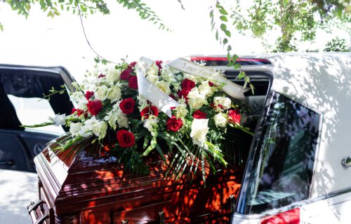 Sarg mit Blumen in Leichenwagen